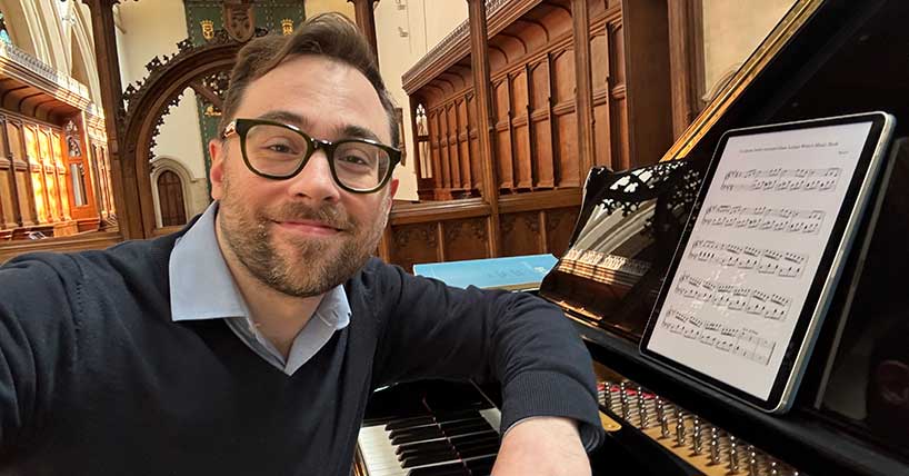 Dr Andrew Frampton sitting at a piano. Photo by Andrew Frampton