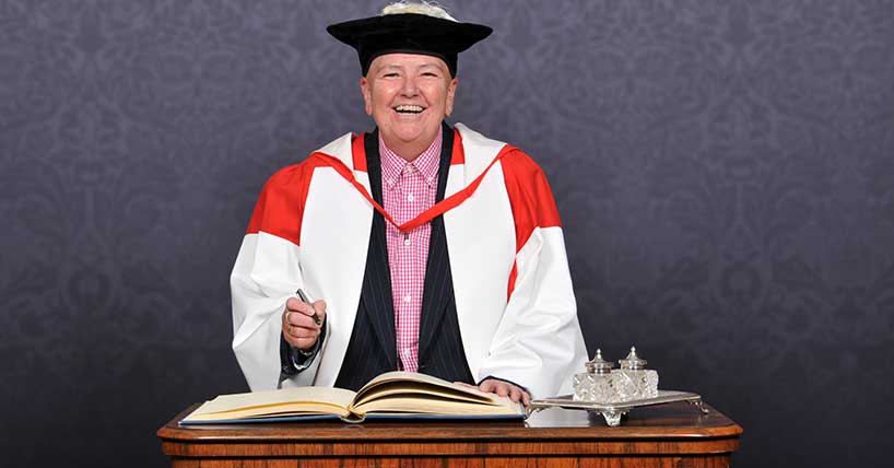 A picture of Huffty McHugh signing the book for her honorary degree