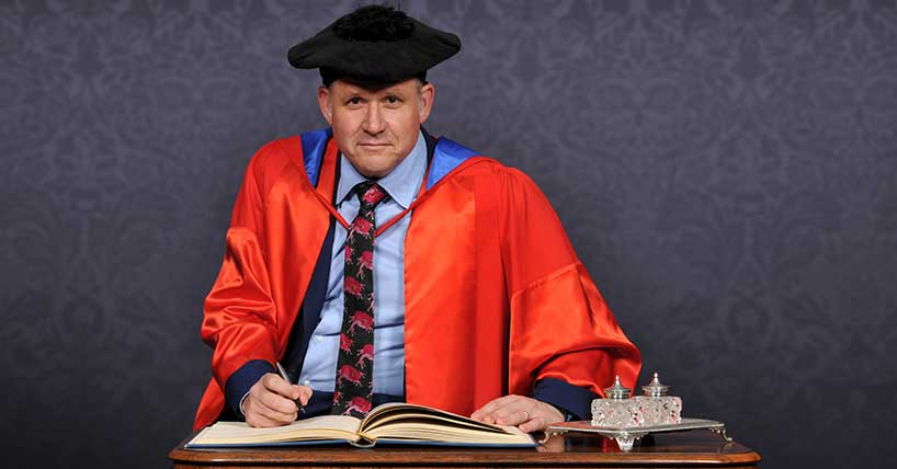 Henry Dimbleby signing the book at his honorary degree ceremony