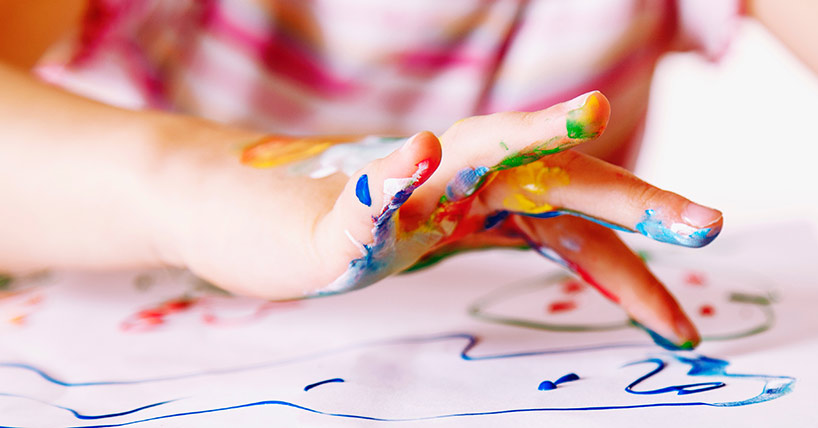 young girl painting with colorful hands